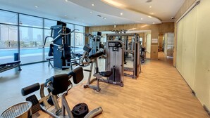Et fitnessrum med diverse træningsmaskiner, store vinduer og et trægulv.