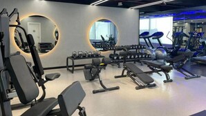 Uma academia com equipamentos de ginástica, espelhos e esteiras.