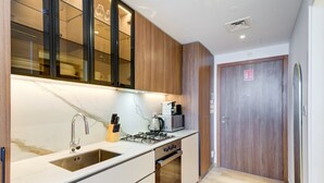 Cozinha compacta com pia, fogão e micro-ondas, armários de madeira e uma porta com uma placa.