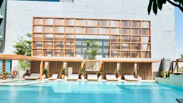 Piscina com espreguiçadeiras e estrutura de vedação em madeira.