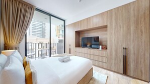 Quarto de hotel moderno com uma cama grande, televisão e varanda com vista para a cidade.