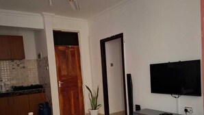 Ein Schlafzimmer mit Bett, Deckenventilator, Fernseher, einem kleinen Tisch und einer Topfpflanze.