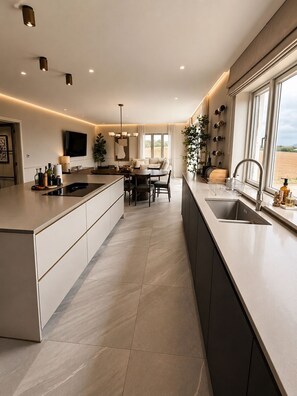 Una cocina moderna con una isla central, una zona de comedor con una mesa redonda y un gran ventanal con vistas al exterior.