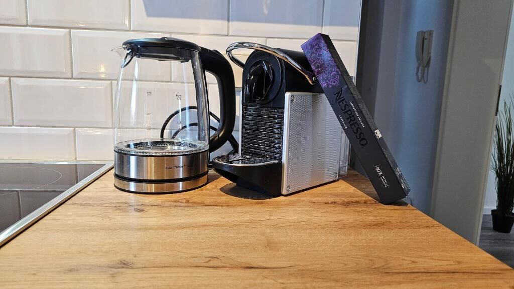 Una cuina amb cafetera, bullidor i torradora sobre un taulell de fusta.
