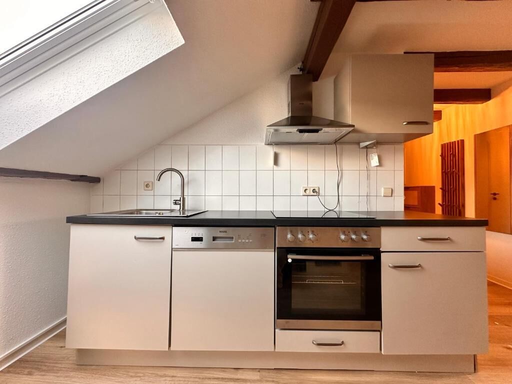 Een moderne keuken met een ingebouwde vaatwasser, oven en een raam boven de spoelbak.
