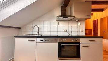 Een moderne keuken met een ingebouwde vaatwasser, oven en een raam boven de spoelbak.