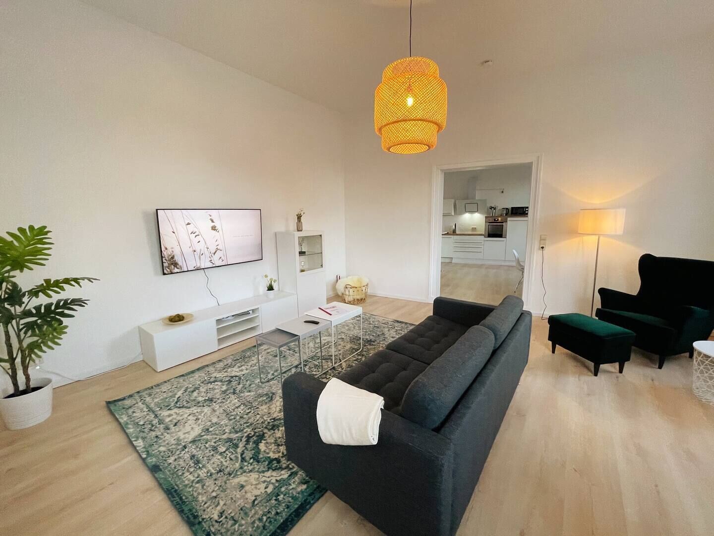 Un salon moderne avec un canapé, un téléviseur et un luminaire suspendu.