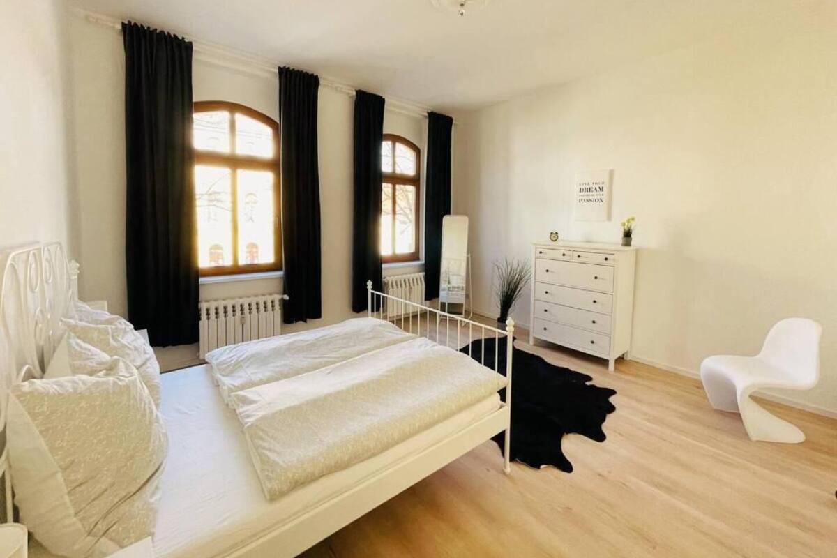 Un dormitorio con cama, cómoda, silla y radiador.