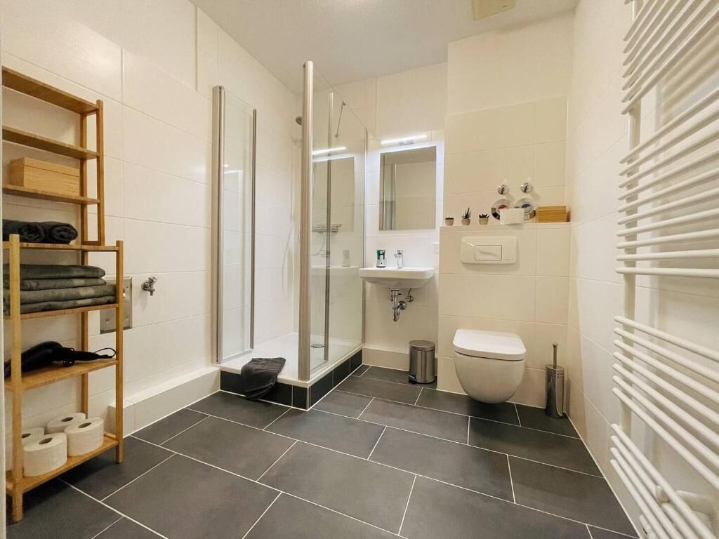 Une salle de bain moderne équipée d’une douche, de toilettes et d’un lavabo.