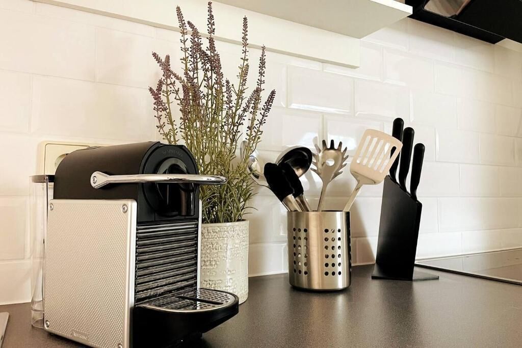 A kitchen counter with a coffee machine, a potted plant, and a utensil holder.
