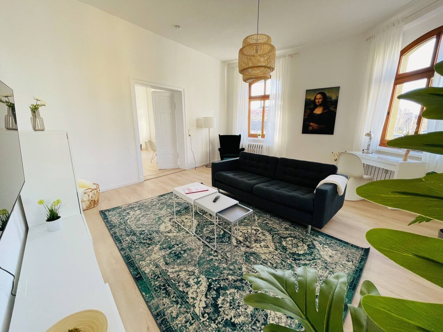 Una sala de estar moderna con un sofá, una mesa de centro, una alfombra grande y un cuadro en la pared.
