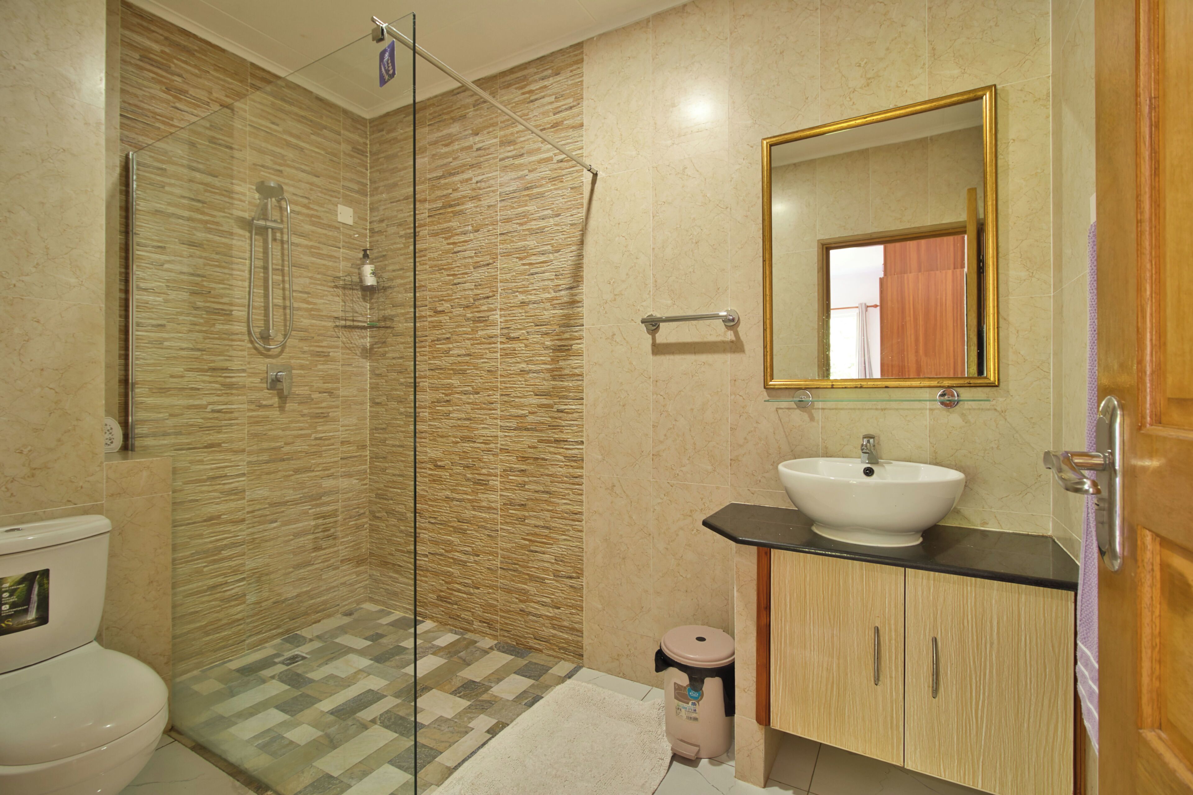 A bathroom with a glass-enclosed shower, a toilet, a sink, and a mirror.