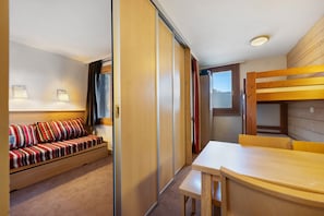 Una habitación con sofá, mesa y literas.