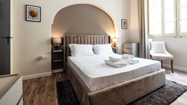 Ein Schlafzimmer mit Bett, Nachttischen, einem Sessel und einem Fenster.