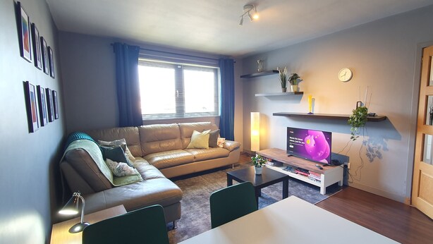 A living room with a sofa, a coffee table, a TV, and a bookshelf. - 2BR- Modern, top floor apartment  -  Free parking fast internet.  Near hospitals (Aberdeen)