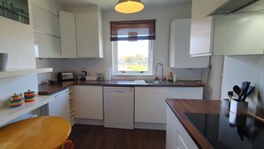 A compact kitchen with white cabinets, a wooden countertop, a built-in dishwasher, and a window with blinds. - 2BR- Modern, top floor apartment  -  Free parking fast internet.  Near hospitals (Aberdeen)