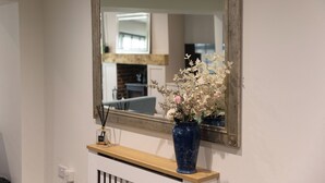 A mirror above a wooden shelf with a vase of flowers and a bottle of perfume. - The Old Sawmill (Newcastle-upon-Tyne)