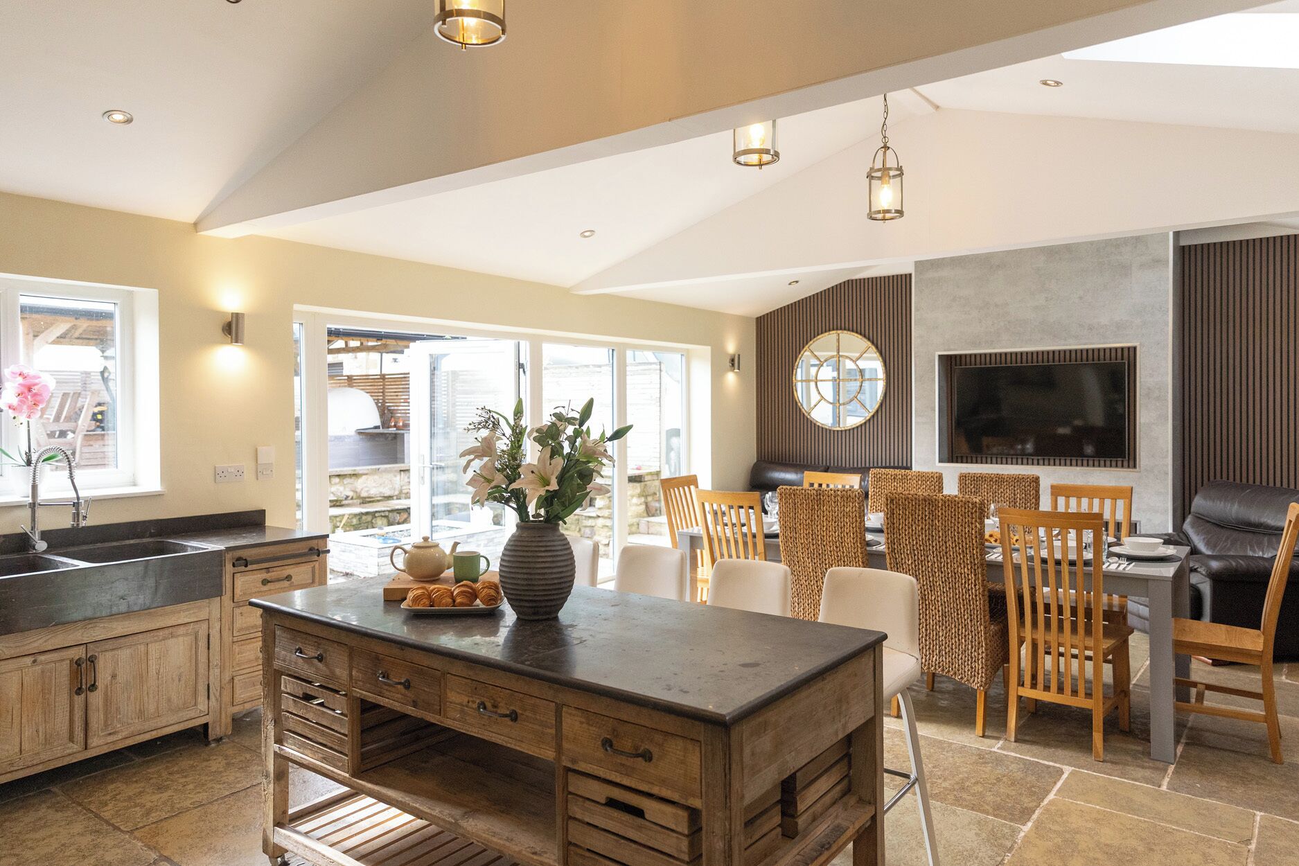 A spacious kitchen with a central island, wooden cabinets, and a dining area with wicker chairs.