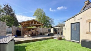 A backyard with a wooden pergola, a barbecue area, and a door. - The Old Sawmill (Newcastle-upon-Tyne)