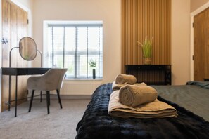 A hotel room with a bed, a desk, a chair, a window with blinds, and a potted plant. - The Old Sawmill (Newcastle-upon-Tyne)