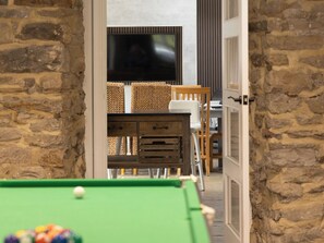 A billiards table with balls, a television in the background, and a stone wall. - The Old Sawmill (Newcastle-upon-Tyne)