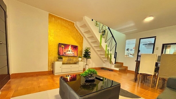Ein modernes Wohnzimmer mit Treppe, Flachbildfernseher, Sofa und Couchtisch.