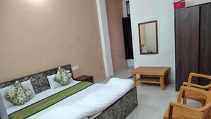 Un dormitorio con una cama, una silla de madera, una mesita de noche, un espejo y un armario.