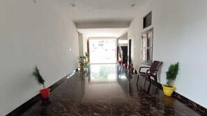 Un pasillo con piso pulido, plantas en macetas y una silla.