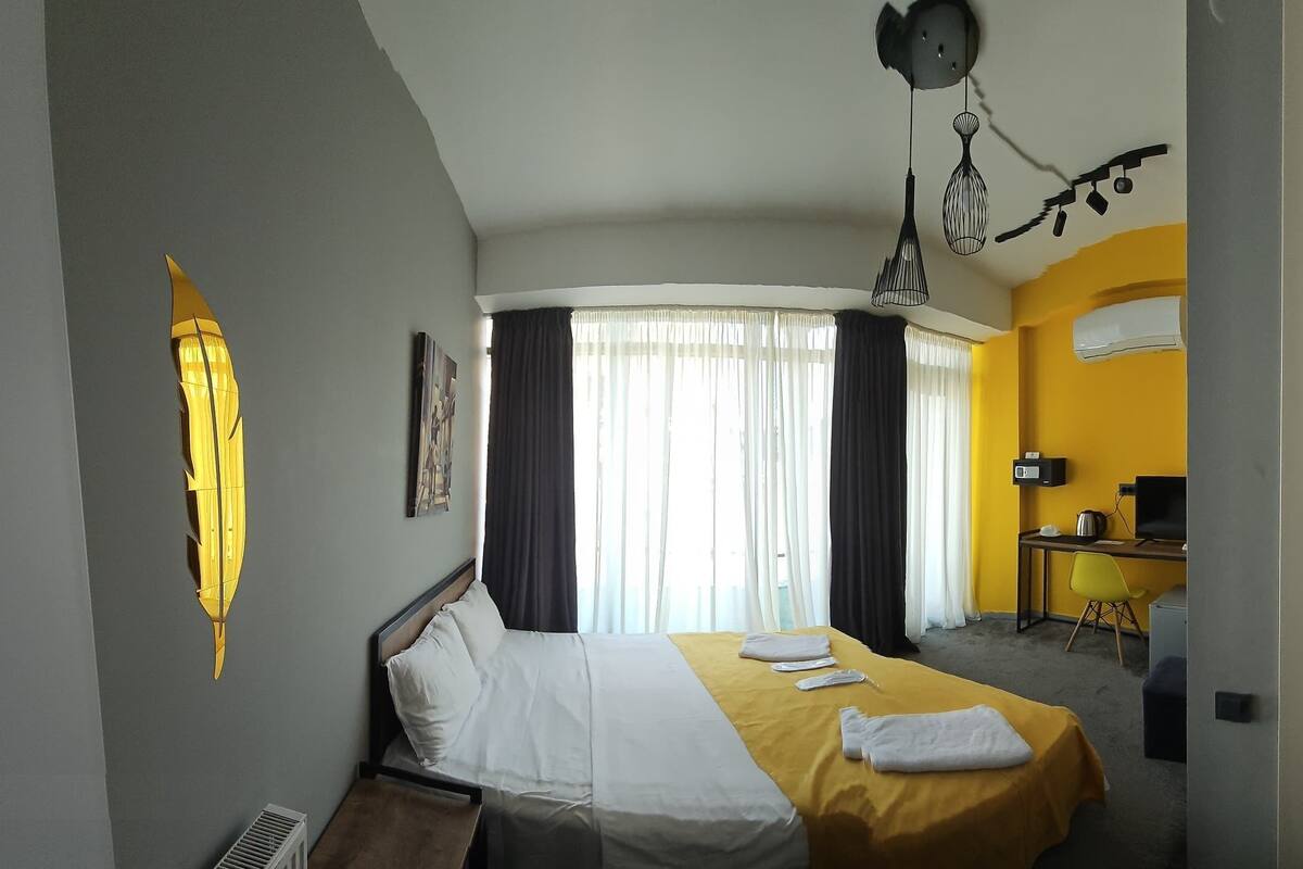 Habitación de hotel con cama, escritorio, silla, aire acondicionado, televisión y baño.