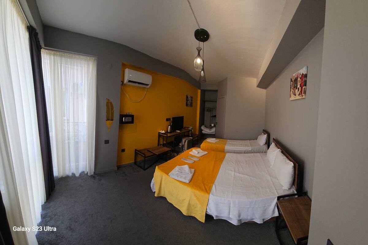 Una habitación de hotel con dos camas, un escritorio, un equipo de aire acondicionado y un cuadro en la pared.