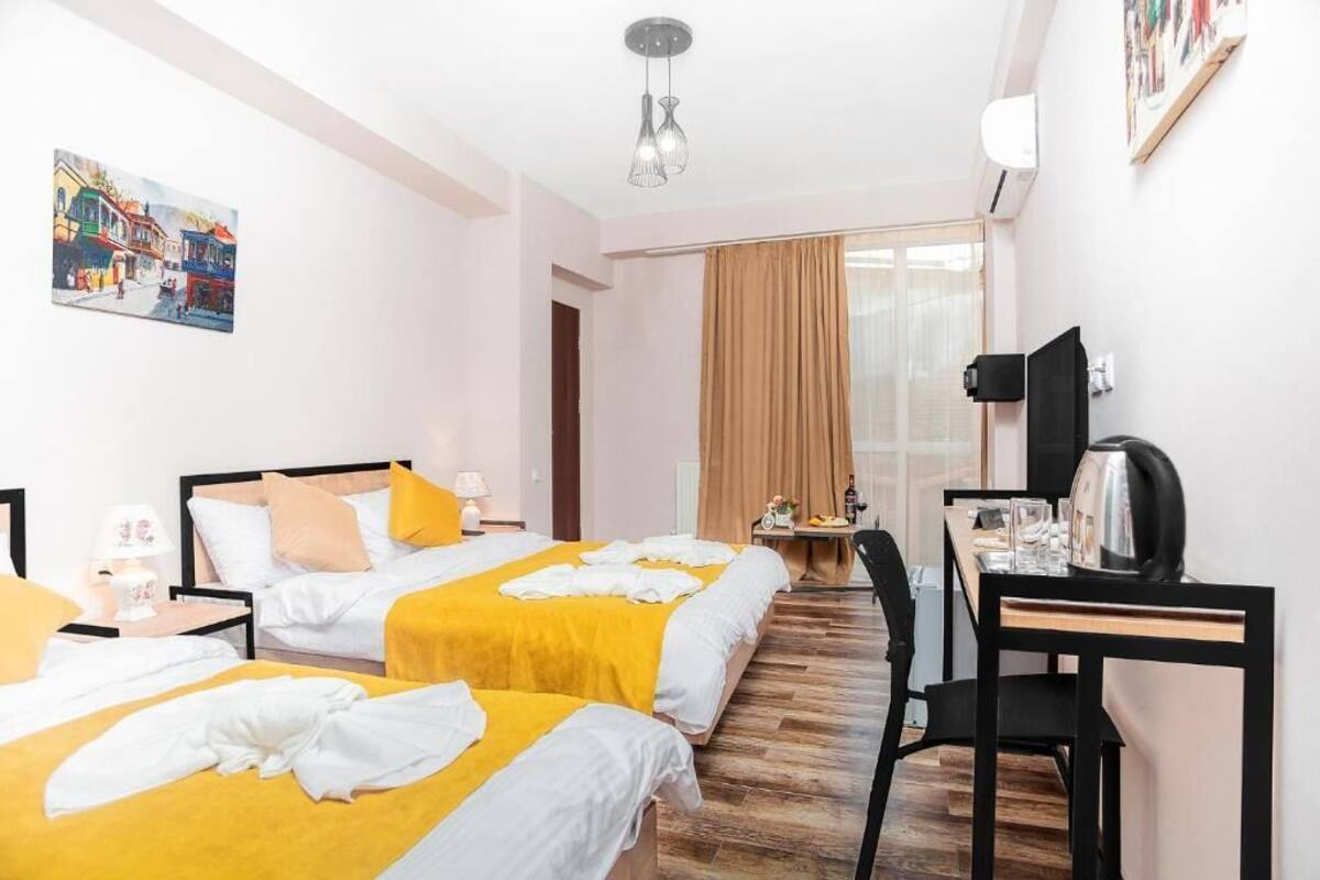 Habitación de hotel con dos camas, un escritorio, una silla, un televisor y un cuadro en la pared.