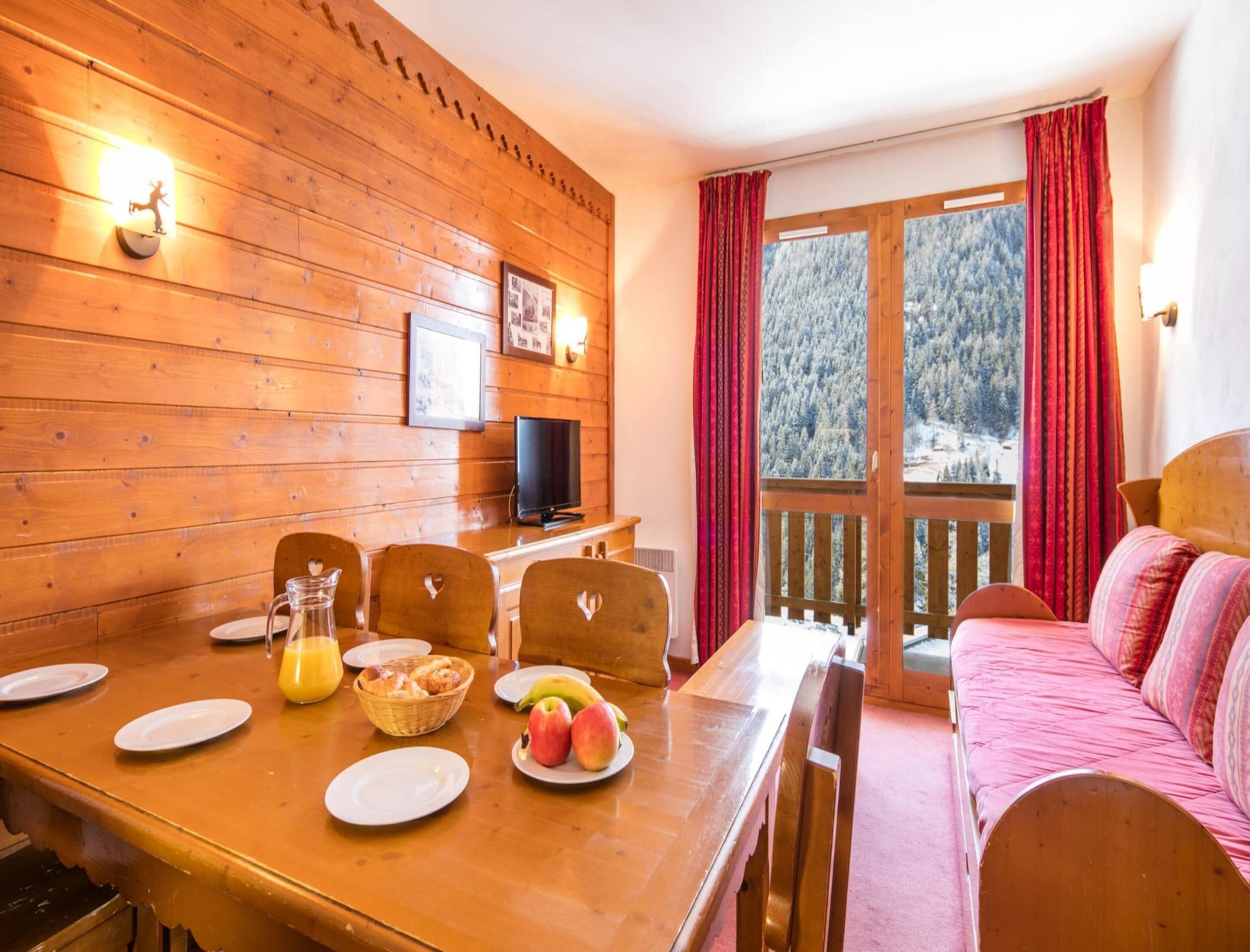 Un intérieur en bois comprenant une table à manger, des chaises, un téléviseur et un canapé.