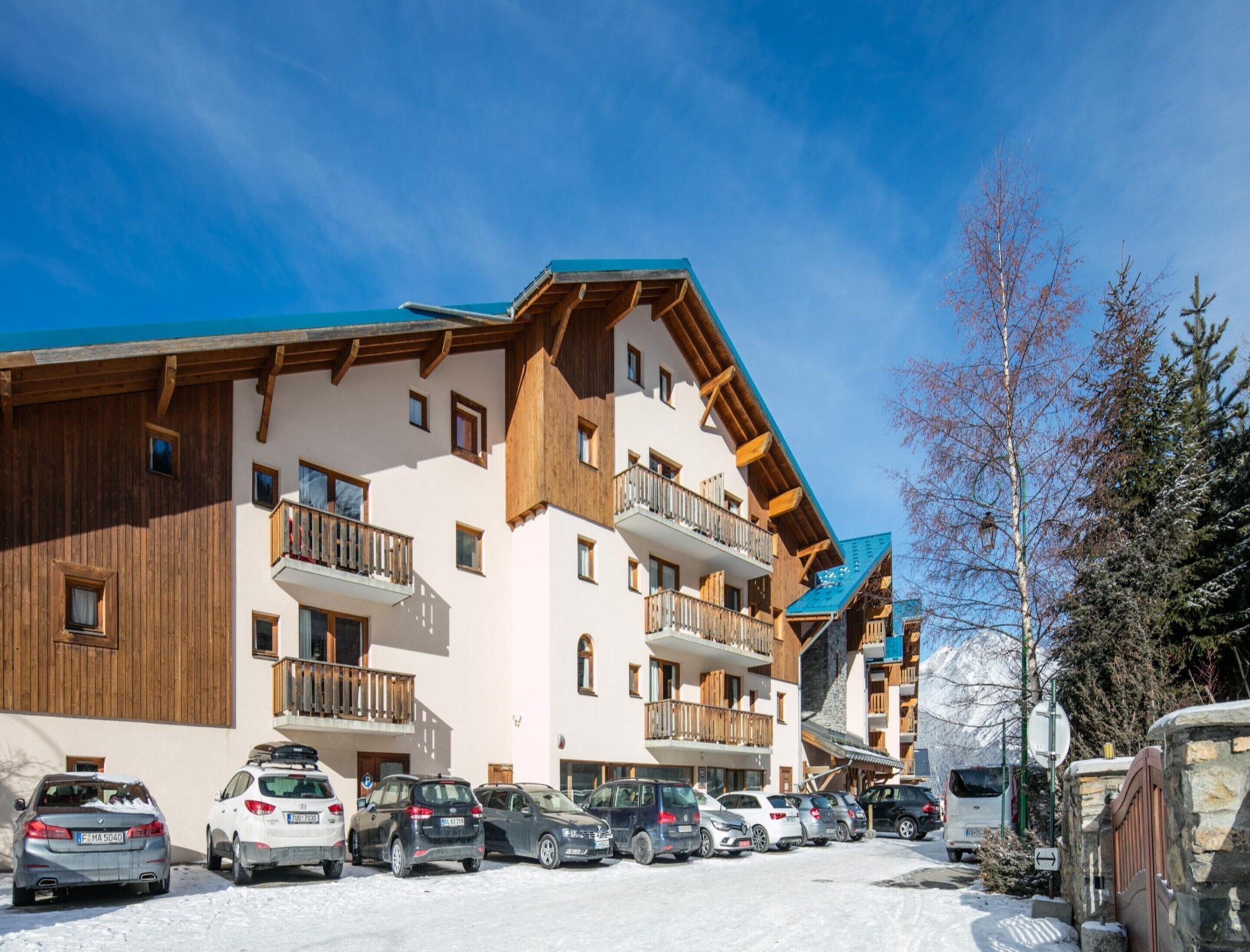 Un hôtel à plusieurs étages doté de balcons, d’un parking et d’un terrain enneigé.