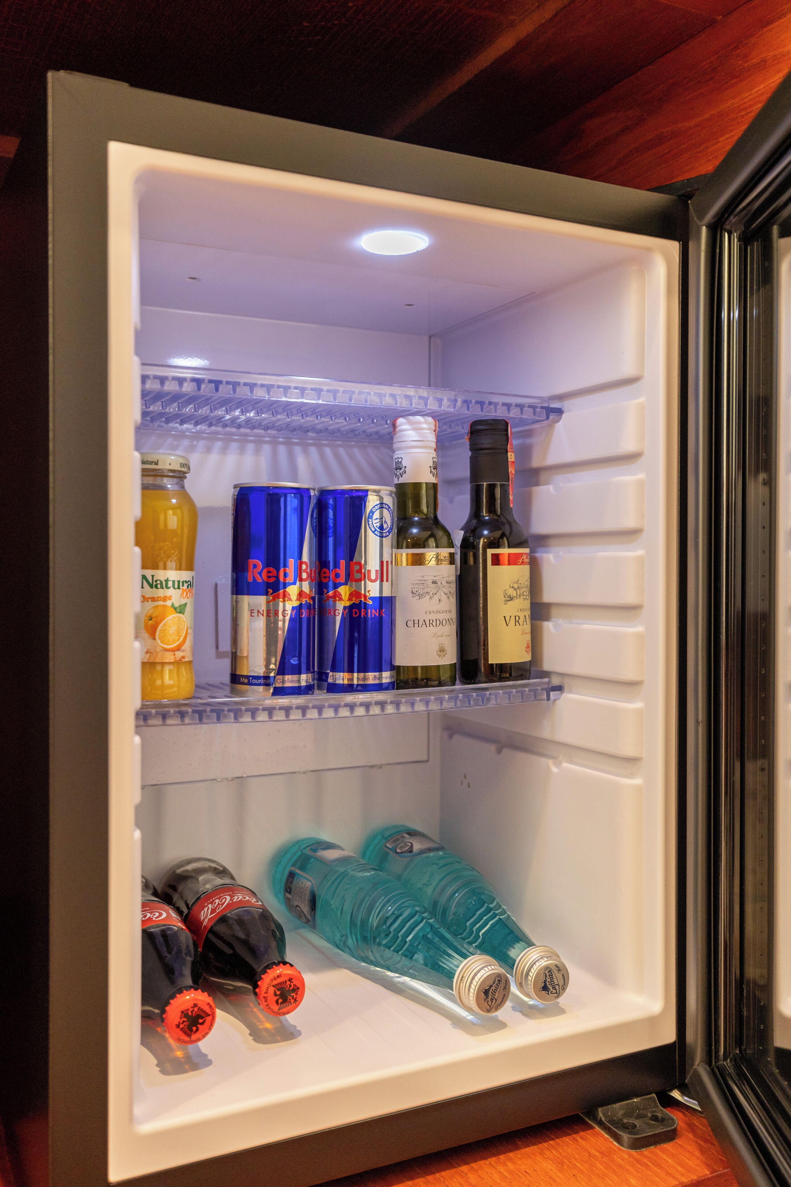 Un refrigerador con bebidas y botellas en su interior.