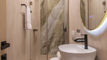 Un baño moderno con un espejo grande, un lavabo y una cabina de ducha.