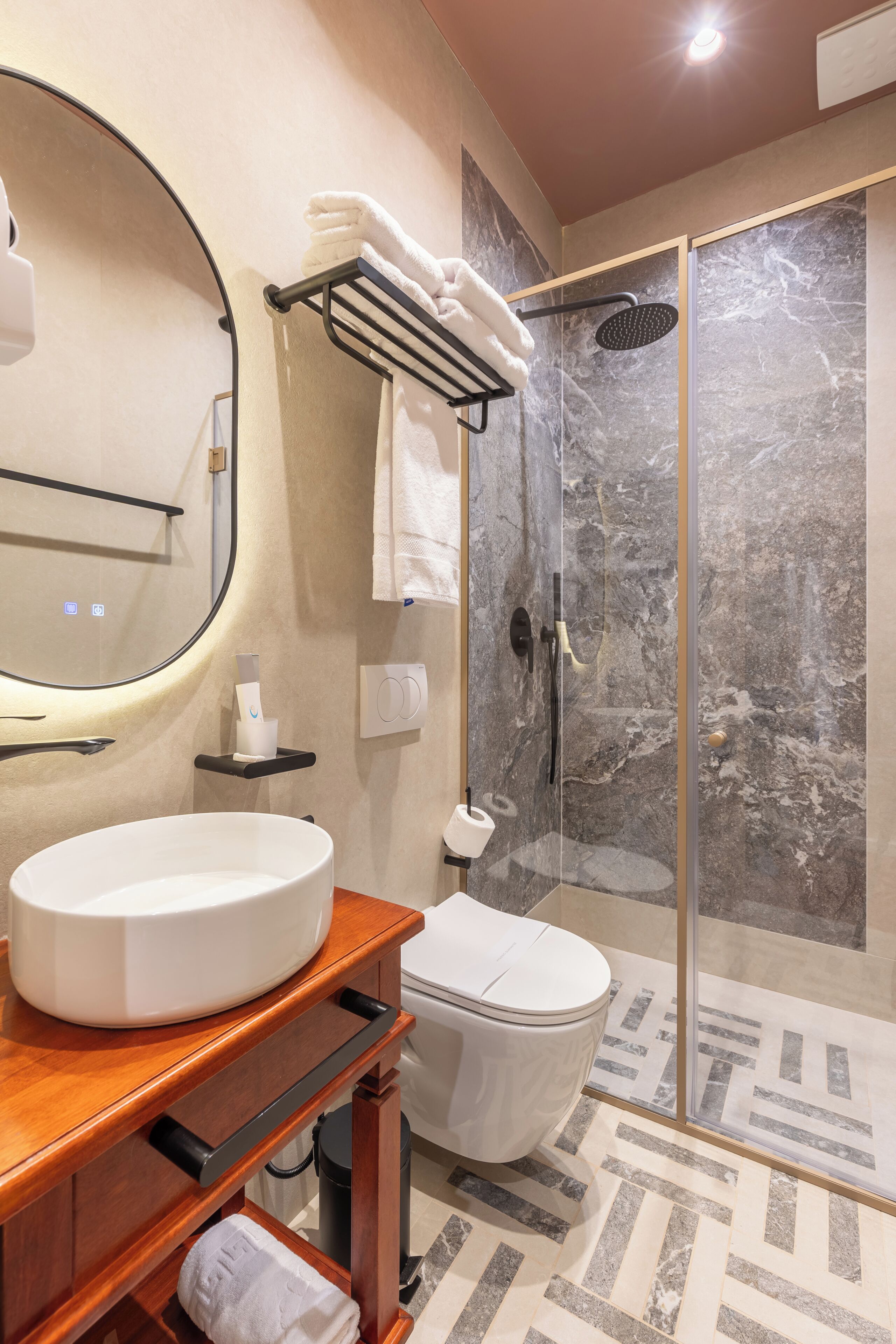 Une salle de bain moderne avec un lavabo rond, des toilettes et une douche à parois de verre.