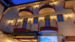 A multi-story building with balconies, exterior lighting, and a television screen.