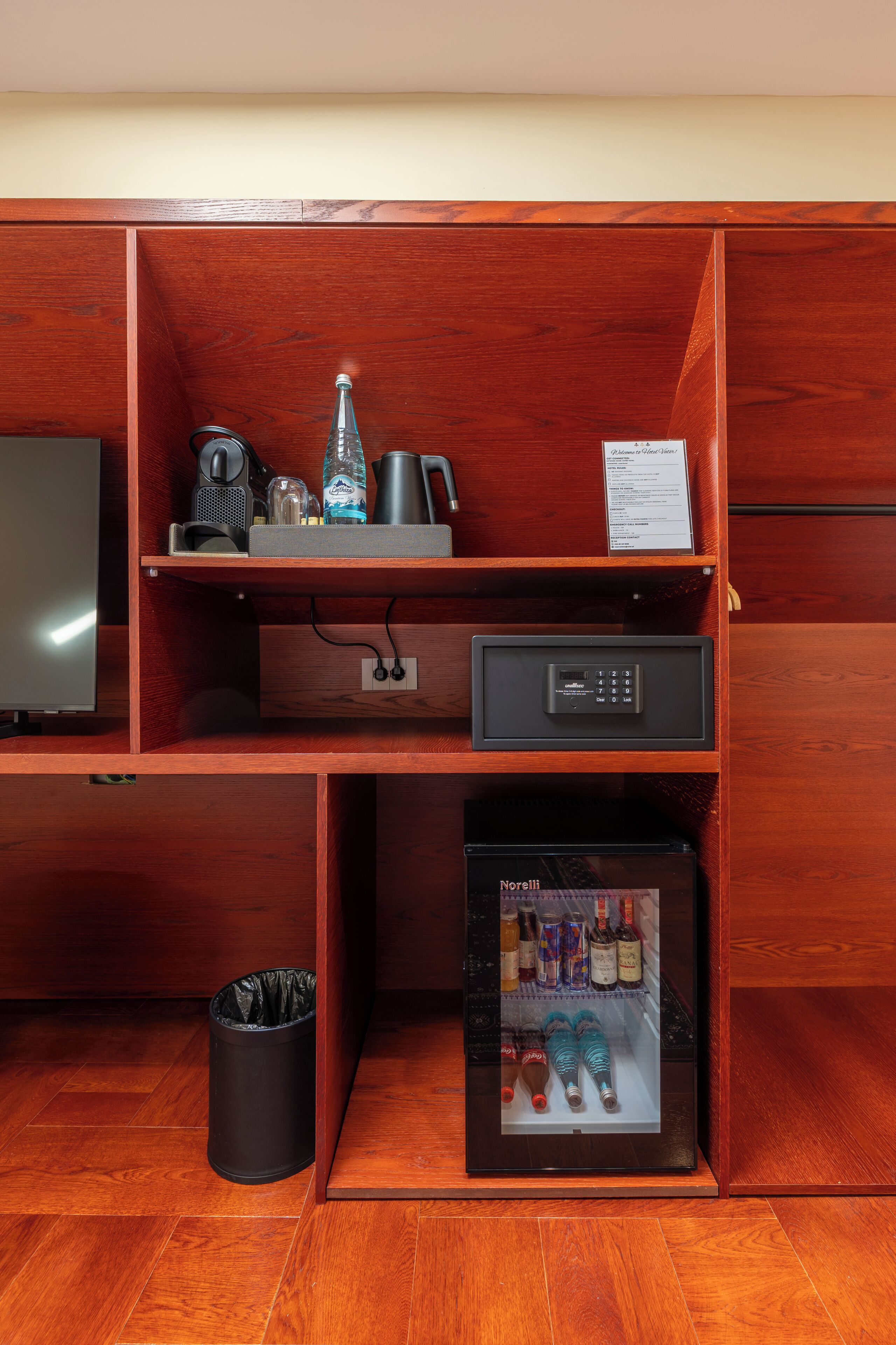 A wooden entertainment center with a television, a coffee maker, a speaker, and a small refrigerator.