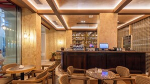 A bar area with wicker chairs, a bar counter, and shelves of bottles.