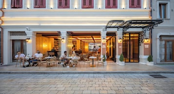 Ein Café mit Sitzgelegenheiten, einer Bar und dem Eingang eines Hotels.