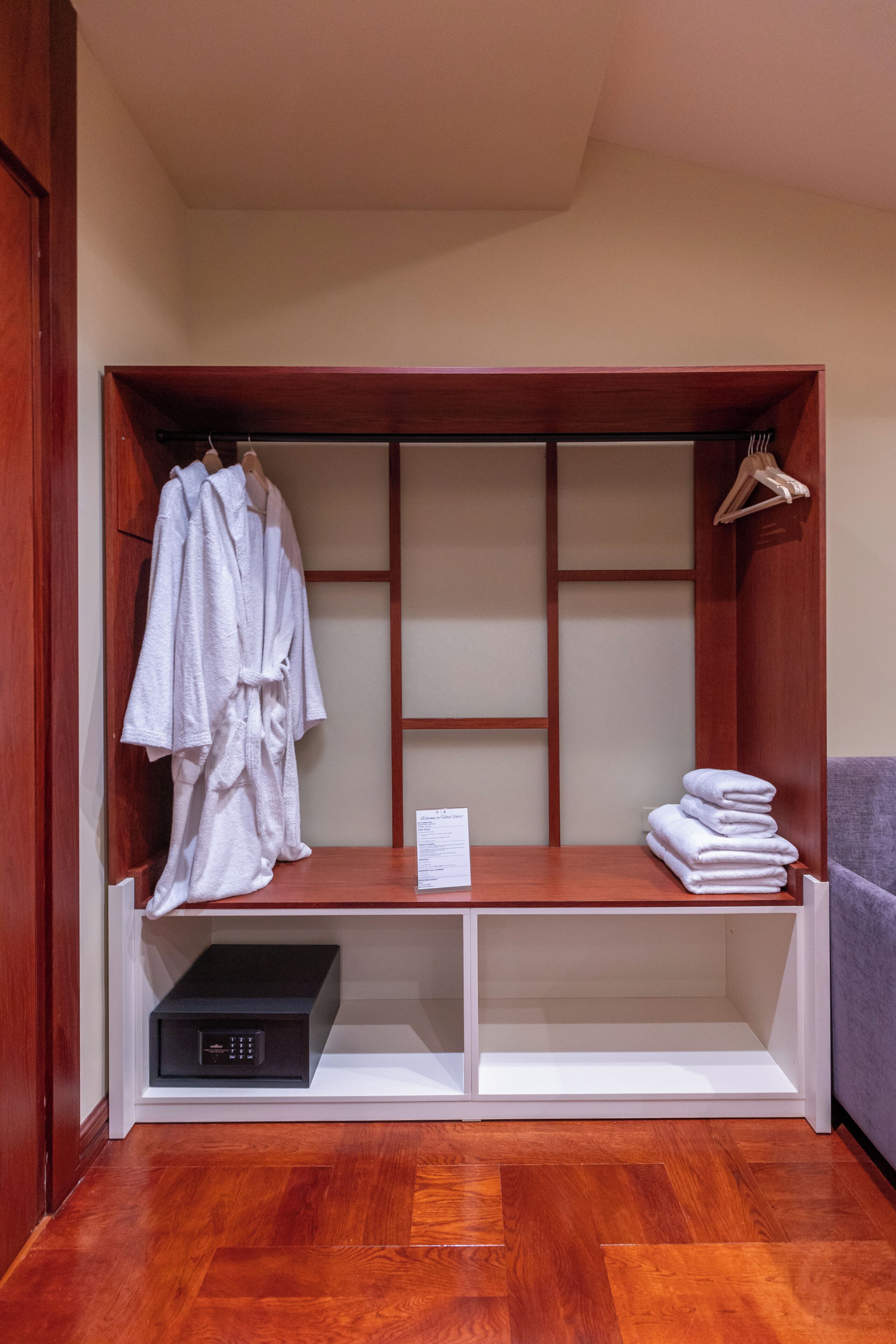 Un dressing avec des étagères en bois, une tringle à vêtements et une pile de serviettes pliées.