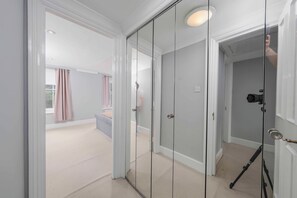 Ein Zimmer mit einem großen Spiegel, einer Kamera auf einem Stativ und einer Tür zu einem anderen Raum.