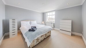 A bedroom with a bed, a dresser, a radiator, and a window. - The Marylebone Hacienda (London)