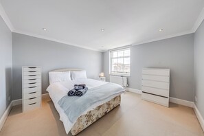 Ein Schlafzimmer mit einem Bett, einem Schminktisch, einem Heizkörper und einem Fenster.