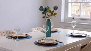 A dining table set with plates, cutlery, and a vase with flowers. - The Marylebone Hacienda (London)