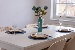 Ein Esstisch gedeckt mit Tellern, Besteck und einer Blumenvase.