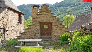 Ein Steinhaus mit einer Holztür und einer Holzbank davor.