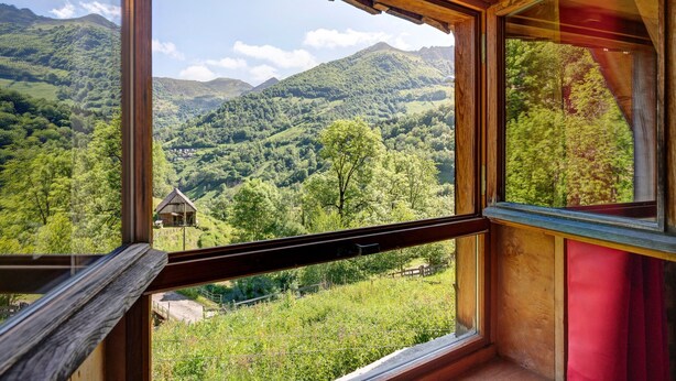 Ein Zimmer mit großen Fenstern und Blick auf eine gebirgige Landschaft.