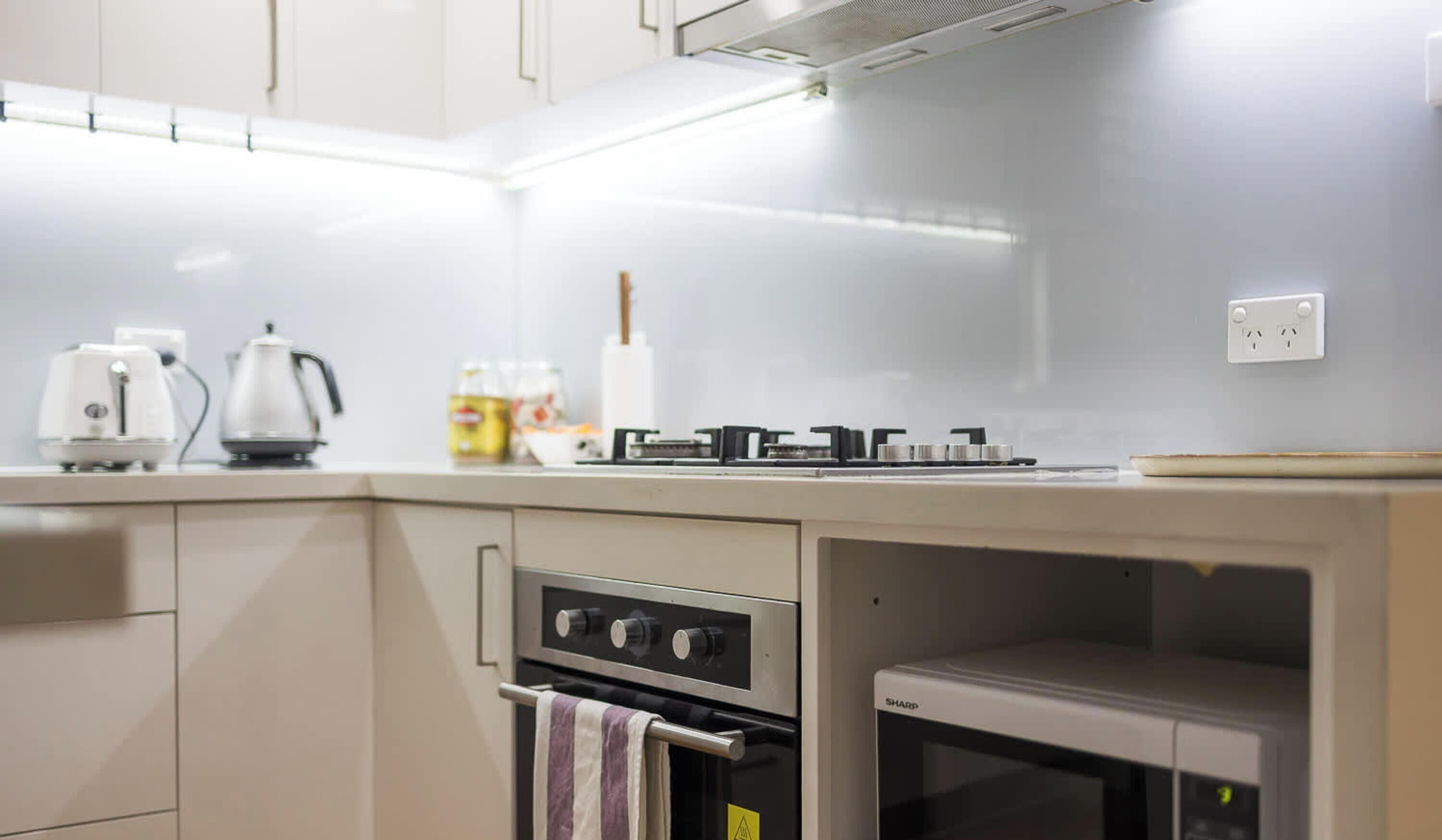 A modern kitchen with a built-in oven, a coffee maker, and a kettle on the countertop.