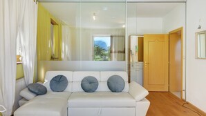 A modern living room with a white sofa, a glass partition, and a view of the outdoors. - Apartment 'Sonnenresidence Alpenhof' with Mountain View, Balcony and Wi-Fi (Termeno sulla Strada del Vino)